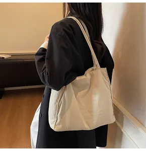Minimalist cream white canvas tote bag shown on model with spacious shoulder carry design