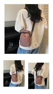 Detail view of pink nylon crossbody bag with black adjustable strap and circular logo