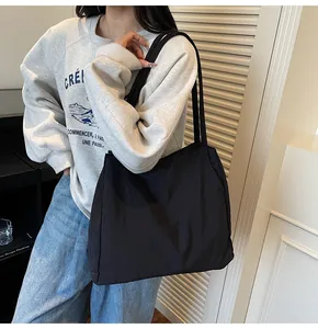 Detail view of black large capacity nylon tote bag with wide shoulder straps on model