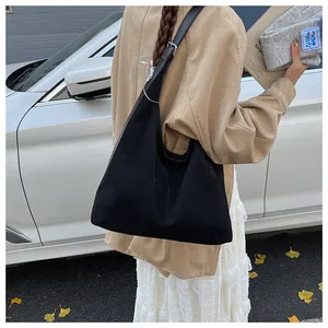 Detail of black large capacity suede tote bag with adjustable strap in autumn street setting