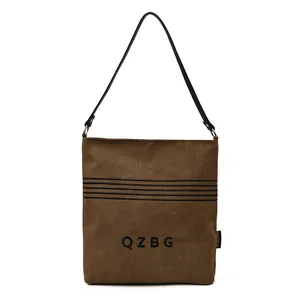 Front view of a brown canvas bucket bag with QZBG letter print and black shoulder strap