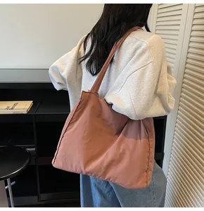 Detail of minimalist brick-red large capacity tote bag worn as a shoulder bag