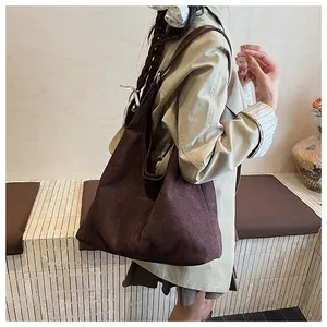 Detail view of large dark brown hobo bag worn by model over a khaki trench coat