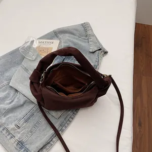 Brown suede cloud bag with knotted handle and inner zip pockets on a stylish background