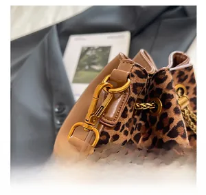 Detail of leopard print bucket bag featuring gold metal hooks and brown leather trim