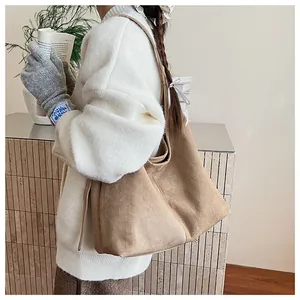 Detail of light brown suede tote bag with vertical stitching and soft matte finish texture