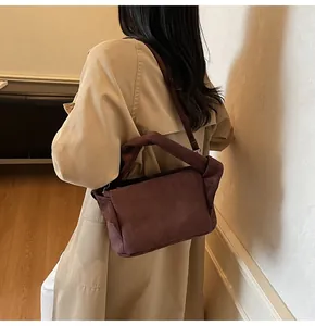 Detail of the unique twisted handle design on this dark brown suede textured handbag