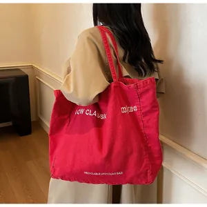 Détail de l'inscription blanche imprimée sur le grand sac cabas en toile rouge