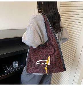 Detail of burgundy leopard print tote bag featuring a front pocket with white Noronoro logo
