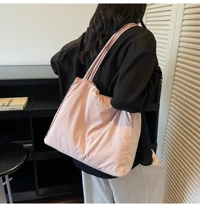 Detail of a large pale pink tote bag worn over the shoulder showing soft matte texture