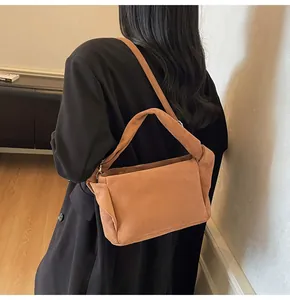 Rear view of model wearing a brown suede crossbody bag with wide handle in chic style