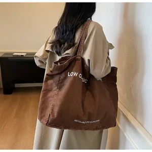 Détail du grand sac cabas en toile marron foncé avec inscription blanche pour femme