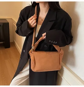 Detail view of brown matte suede shoulder bag with pleated edges and gold hardware
