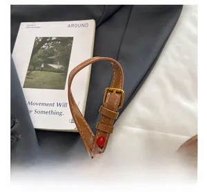 Close-up of adjustable brown leather shoulder strap with vintage gold metal buckle