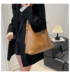 Detail view of large caramel hobo bag in polished leather with stylish side pleats