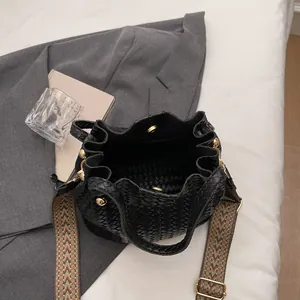 Fashionable black woven bucket bag with patterned wide strap and gold hardware