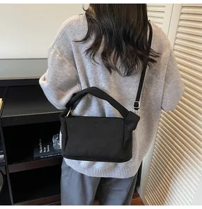 Detail of black nylon pleated bag featuring unique knotted handle and adjustable shoulder strap
