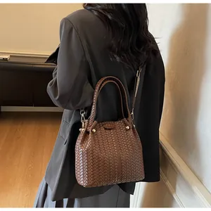 Detailed close-up of dark brown woven leather bucket bag texture with gold hardware