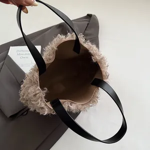 Chic beige plush bucket tote bag with black leather handles shown from a top view perspective