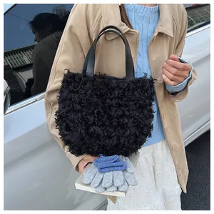 Detail of black faux fur bucket bag with smooth leather handle shown by a model