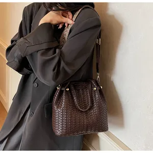 Detail of dark brown woven bucket bag with vintage strap and gold hardware accents