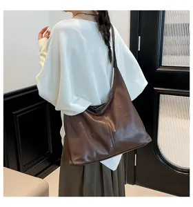 Deep brown large capacity faux leather tote bag showing drape and size on shoulder