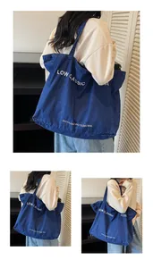 Détail du sac cabas en denim bleu avec logo LOW CLASSIC et texte écologique blanc