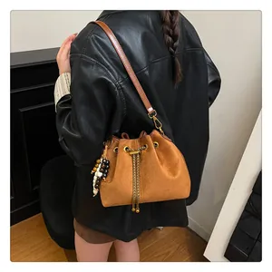 Detail of vintage brown suede drawstring bucket bag with gold chain and beaded charm