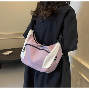 Detail view of the purple and white contrast crescent shoulder bag worn by a model