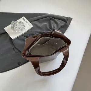 Top view of brown glossy rivet shoulder bag showing spacious interior with zip pocket
