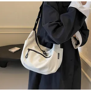Close-up of a white canvas shoulder bag featuring a black zipper pocket and wide strap