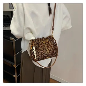 Detail of leopard print bucket bag with drawstring closure and beaded tassels on a model