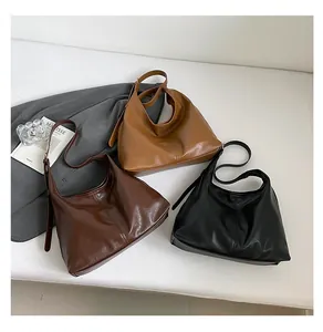 Three hobo tote bags in black, dark brown, and caramel colors with wide shoulder straps