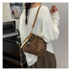 Detail of leopard print bucket bag featuring brown leather strap and gold drawstring beads