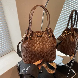 Deep brown woven bucket bag with patterned strap and gold studs for daily commute
