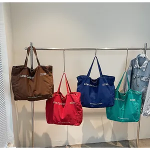 Sacs cabas en toile marron, rouge, bleu et vert suspendus à un support