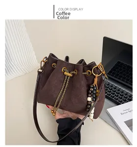 Detail of coffee brown drawstring bucket bag with gold chain and wooden bead charm