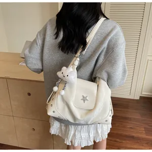 Close-up of white tote bag with silver star clasp, rivets and plush cloud pendant