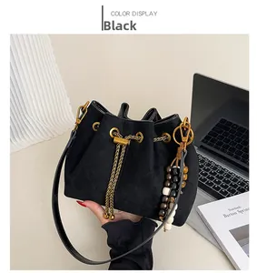 Detail view of black drawstring bucket bag with gold chain and tricolor wooden beads