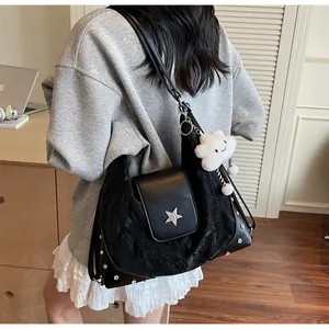 Close-up of black pleated tote bag with silver star and rivets on a shoulder strap