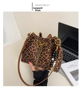 Detailed macro view of a leopard print bucket bag with gold chain and beaded accessory