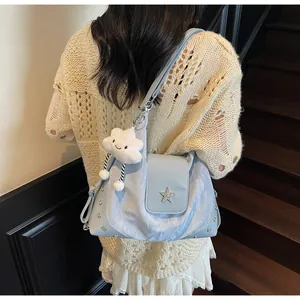 Detail of light blue shoulder bag with star badge and cloud plush charm on a model
