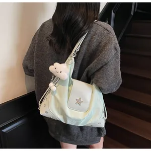 Detail of light green shoulder bag with star emblem and plush cloud charm on model