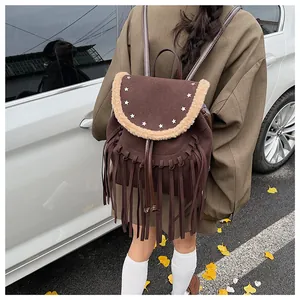 Détail du sac à dos en daim marron avec franges, clous en étoile et bordure en peluche