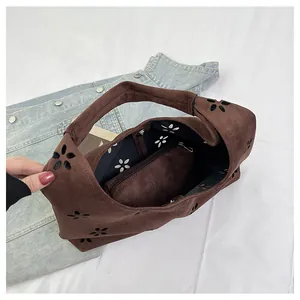 Detail view of suede tote with laser-cut floral patterns and internal zipper pouch