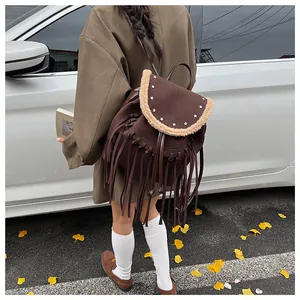 Détail du sac à dos en daim marron avec franges, clous étoiles et bordure peluche