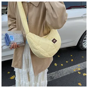 Detail of light yellow quilted crescent bag with heart stitching and leather patch