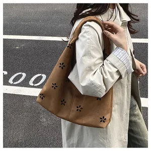 Detailed close-up of brown suede tote bag with laser-cut floral patterns for commuting