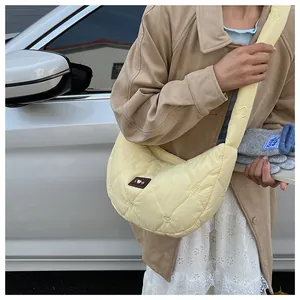 Detail of light yellow cloud bag featuring heart quilting and wide adjustable strap