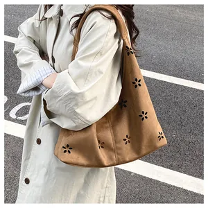 Close-up of brown suede tote bag featuring intricate laser-cut floral hollow patterns
